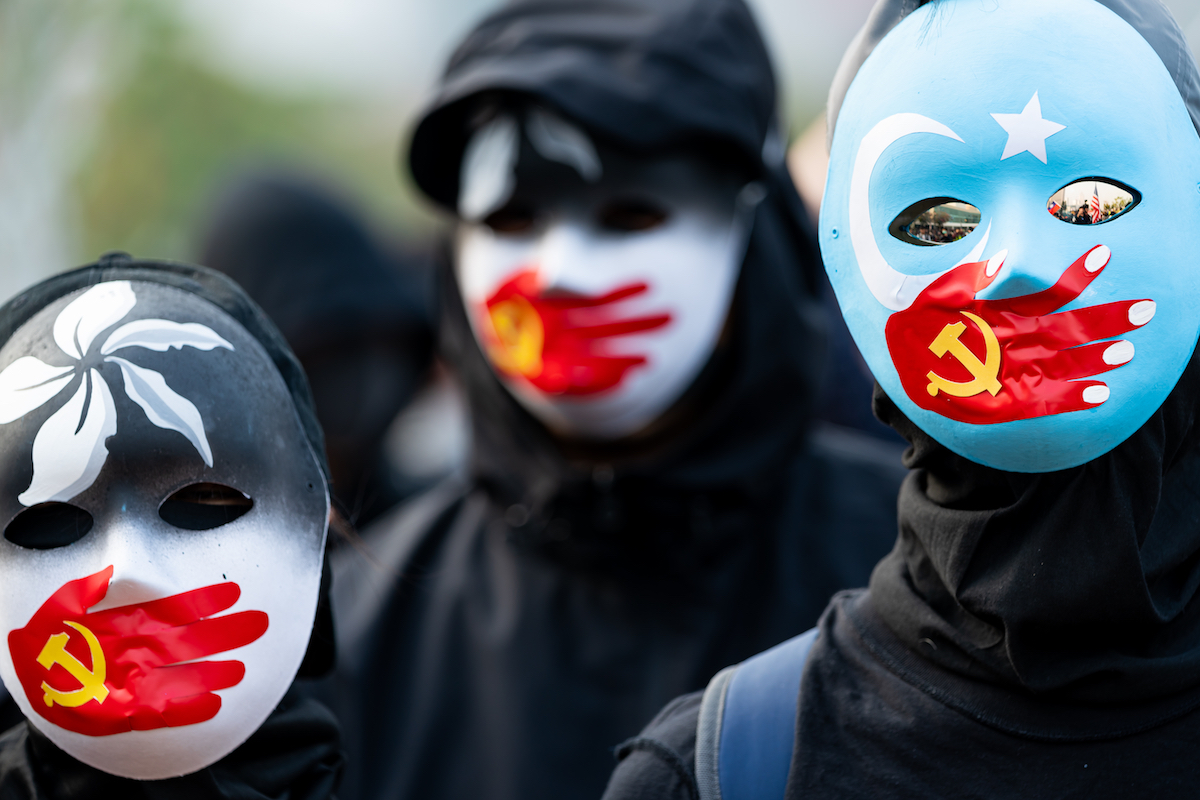 HONG KONG - DECEMBER 22 2019: A group of protestors wear masks symbolizing the Communist Party of China's silencing of Uyghur Muslims and the Hong Kong pro-democracy movement at a rally in Hong Kong. HONG KONG - DECEMBER 22 2019: A group of protestors wear masks symbolizing the Communist Party of China's silencing of Uyghur Muslims and the Hong Kong pro-democracy movement at a rally in Hong Kong.