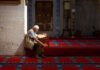 Un homme lit le Coran dans une mosquée