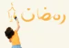 Une petite fille écrit ramadan sur un mur