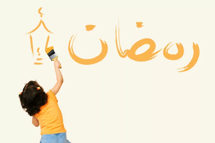 Une petite fille écrit ramadan sur un mur